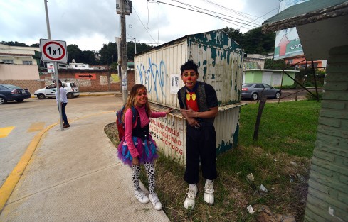Una pareja de artistas callejeros esperan el próximo camión para presentar su show con el que llevan el sustento a casa.