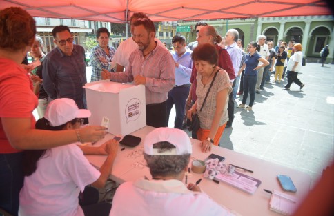 Con algunas fallas en la aplicación del teléfono, uno a uno los ciudadanos emiten su voto mientras una de las funcionarias apunta en una libretita endemientras.  