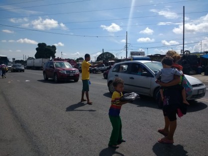 Familias completas, jóvenes en bola y adultos se apostan a la orilla de la carretera arriesgando su vida para pedir a los automovilistas una ayuda. 