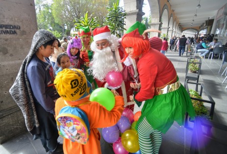 Jóvenes vestidos de Santa Claus y duendes regalaron pelotas a los niños que se encontraban por el camino, a la vez que promocionaban su  show para fiestas infantiles.  