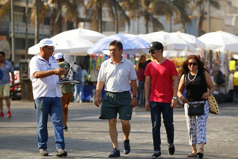 Turistas disfrutan de un día soleado en el paseo del malecón. Vendedores, entre ellos menores de edad, y sacamonedas, los abordan para obtener alguna ganancia de la derrama económica que dejan a su paso.