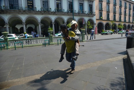 Un joven ayuda a una persona de la tercera edad, cargándolo en su espalda.