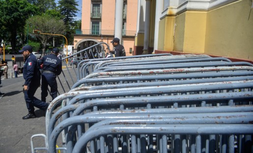Elementos de Seguridad Pública bajan las vallas que serán colocadas el día de mañana duránte el entierro del Cardenal Sérgio  Obesoa