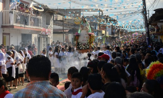 Miles de personas locales y visitantes disfrutan de las danzas y de los coloridos trajes  durante el recorrido del arco por la calle principal del municipio. 
