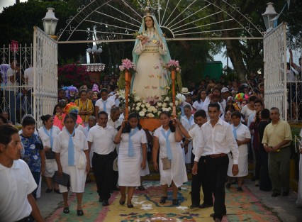 Miles de personas locales y visitantes disfrutan de las danzas y de los coloridos trajes  durante el recorrido del arco por la calle principal del municipio. 