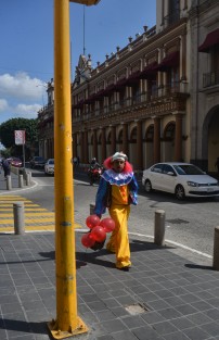 Un hombre vestido de payaso camina por la calle de Enríquez  dónde  vende globos y se toma fotos .