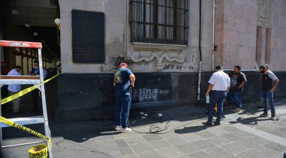 Trabajadores del Palacio de Gobierno de Veracruz intentan remover las pintas realizadas por feministas durante su protesta en días pasados.