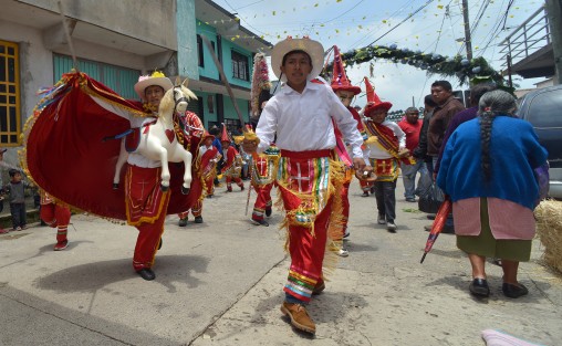Danzantes tradicionales de la región llegan para acompañar la procesión que recorre distintos altares colocados por todo el pueblo, y donde son recibidos por los <em>mayordomos</em> de cada lugar.
