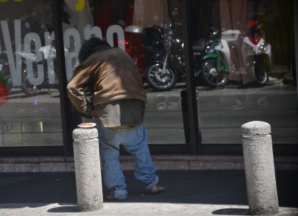 Un hombre en situación de calle camina frente a una tienda departamental del centro de Xalapa.