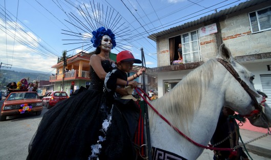 Jovencitas caracterizadas de la  santa muerte, automóviles adornados con flores e imágenes acompañan durante el recorrido del arco floral, que es cargado por los creyentes hasta la puerta del panteón de ese municipio, donde habrá de ser colocado.