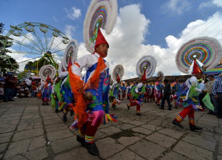 Danzantes multicolores y de todas las edades bailan en atrio de la iglesia para mostrar su fe al Padre Jesús.