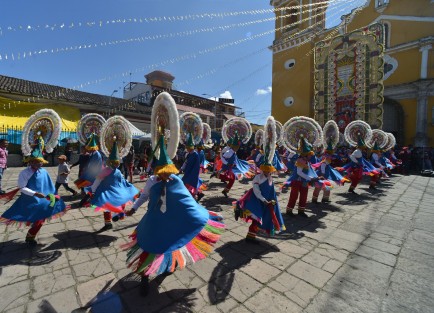 Danzantes multicolores y de todas las edades bailan en atrio de la iglesia para mostrar su fe al Padre Jesús.