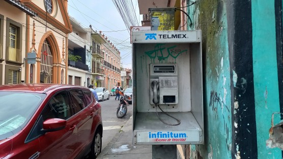 Pese a ser ya sólo un cascarón inservible, los alguna vez teléfonos públicos de monedas de Telmex siguen sin ser retirados de las calles. Un ejemplo éste en la angosta acera de la calle Úrsulo Galván. 