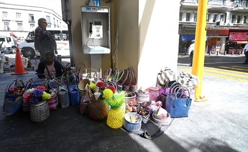 Una señora vende sus canastas en los arcos de palacio de gobierno.
